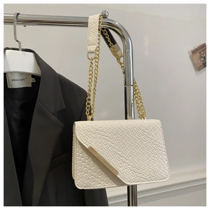 Détail du sac bandoulière crème texturé avec chaîne dorée et garniture en métal