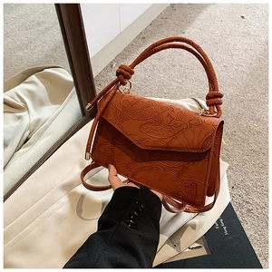 Détail de motifs de poisson et lotus gaufrés sur un sac bandoulière rouge rouille