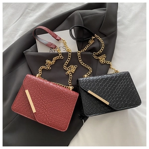 Détail de sacs bandoulière tressés en rouge et noir avec garnitures dorées et chaînes