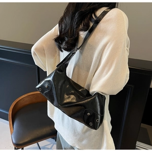 Dettaglio borsa a spalla in pelle nera lucida con borchie argentate e tracolla ampia