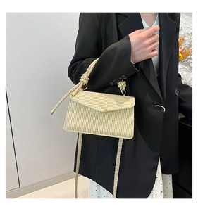 Detail of a beige woven rectangle bag featuring a unique thick rope decorative knot handle