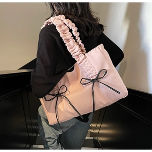 Pink nylon tote bag with black bow details and gathered ruched strap shown on model