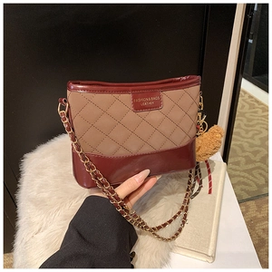 Détail des coutures matelassées et logo en cuir sur sac hobo marron avec chaîne
