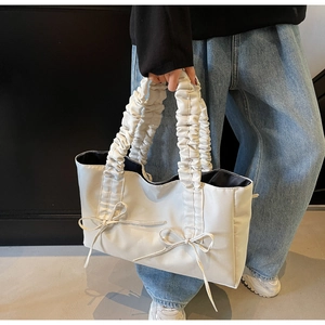 Detailed view of white tote bag with ruffled cloud handle and bow ribbons on the surface