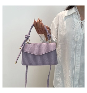 Detail of purple woven texture bag with geometric flap and stylish knot handle