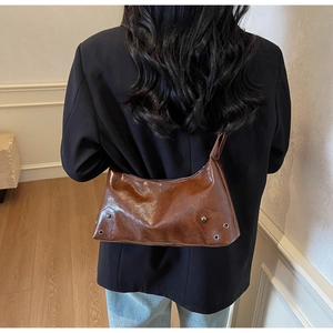 Dettaglio della borsa hobo marrone vintage con rivetti metallici e pelle lucida