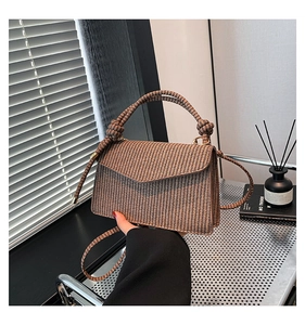Close-up of retro brown woven texture handbag with knot detail and sleek shoulder strap