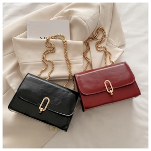 Flat lay of small crossbody flap bags in black and wine red with gold metal chain straps