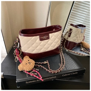 Détail du sac hobo matelassé beige et bordeaux avec chaîne dorée et breloque ourson