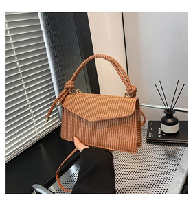 Detailed texture of brown raffia woven handbag with knotted handle and metal hardware