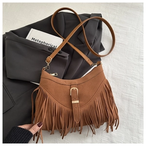 Detail of a brown suede shoulder bag featuring long fringe tassels and a gold buckle strap