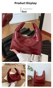 Detail of burgundy high-gloss crescent hobo bag with gold metal handle and embossed text