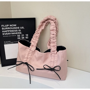Détail du sac cabas rose avec poignée plissée et deux nœuds décoratifs cousus noir et blanc