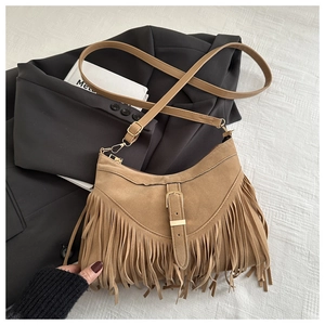 Close-up of brown suede fringe shoulder bag with bohemian tassels and gold buckle detail