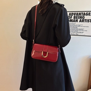 Burgundy patent leather shoulder bag with gold horsebit buckle and slim strap