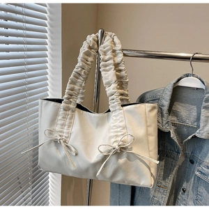 Détail du sac cabas en similicuir crème avec anses plissées et nœuds décoratifs