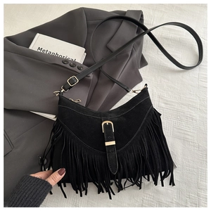 Detail of black suede tassel crossbody bag with golden buckle on elegant gray suit