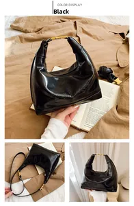 Detail of black glossy leather hobo bag with gold metal handle and embossed logo