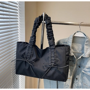 Détail du sac cabas en nylon noir avec poignées plissées, nœuds et surpiqûres blanches