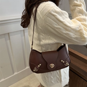 Retro dark brown leather underarm bag with gold lock and rivet details worn by model