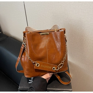 Close-up of brown vintage bucket bag with leather strap and golden chain detail