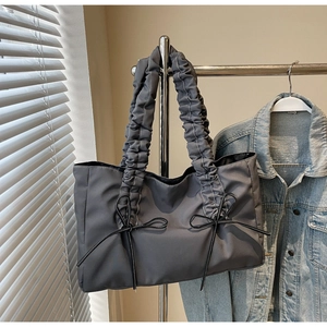 Détail du sac cabas gris avec poignées plissées et nœuds décoratifs en ruban noir