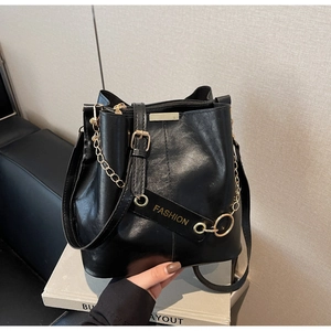Detail of black PU leather bucket bag with gold chain and Fashion tag on white book