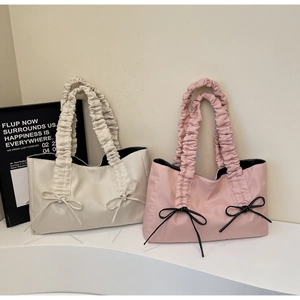 Détail des poignées plissées et des nœuds élégants sur les sacs cabas rose et beige