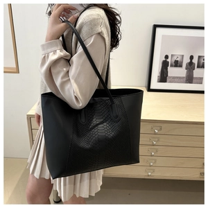 Close-up of black leather tote bag with unique snake pattern embossing and long handles