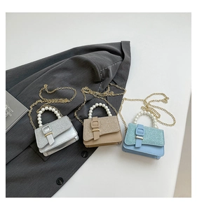 Detailed view of pearl handles and metal chain straps on colorful glitter mini bags