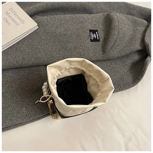 Detalle del bolso tipo cubo de cuero blanco crema con asa de perlas y cadena dorada