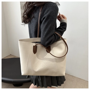 Detail of the minimalist tote bag featuring snakeskin texture and brown contrast straps