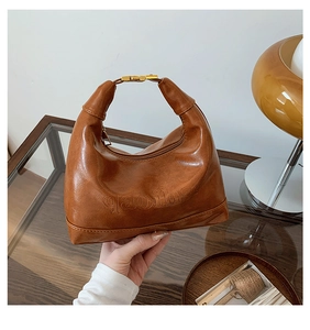 Close-up of caramel hobo bag showing fine leather texture and golden metal buckle details