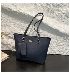 Detail of navy blue tote bag featuring lychee texture and gold metal decorative plaque