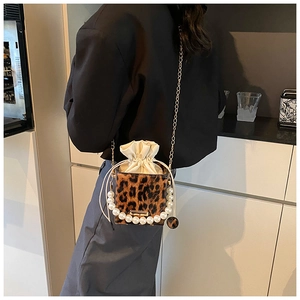 Detalle de bolso tipo cubo de leopardo con asa de perlas y cadena dorada para mujer