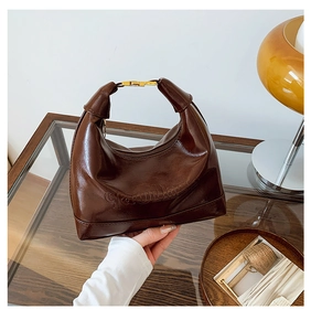 Detailed close-up of dark brown wax leather Hobo bag with gold buckle and embossed text