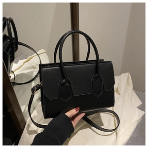 Detail of black rectangular crossbody bag with shield-shaped panels and dual handles
