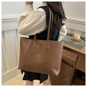 Detailed close-up of brown tote bag featuring snakeskin texture and high-quality stitching