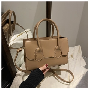 Detail of beige structured handbag with dual round handles and smooth leather texture