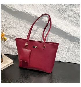 Close-up of burgundy lychee leather tote bag with gold hardware and small pouch