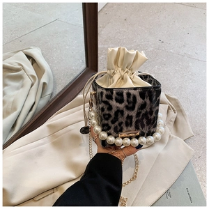 Primer plano del bolso saco de leopardo con asa de perlas y detalles de cadena dorada
