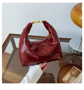 Detail of burgundy patent leather hobo bag with gold buckle and embossed texture
