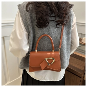 Brown leather crossbody bag with bow detail and gold D-ring shown on model