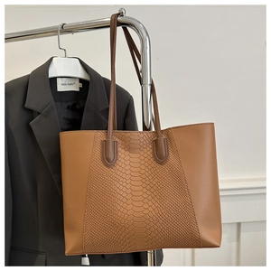 Detail of caramel tote bag featuring exotic snakeskin texture and smooth leather panels