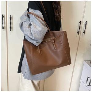 Borsa tote marrone in pelle grana litchi indossata a spalla per un look da ufficio chic