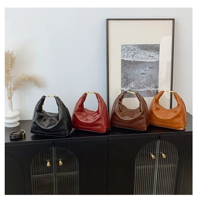 Detail view of four semi-moon handbags in various colors on a vintage black cabinet
