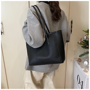 Dettaglio di una borsa tote nera in pelle martellata portata a spalla con stile casual