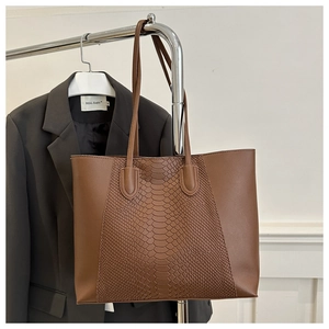 Brown tote bag with snake pattern texture and smooth leather finish hanging on a hanger