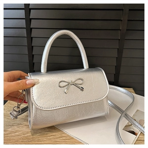 Détail du mini sac à main argenté avec texture métallique, nœud et poignée