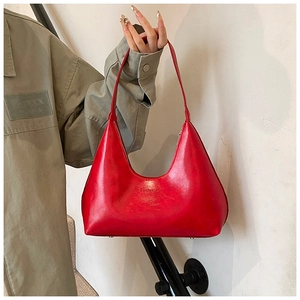 Dettaglio di una borsa a spalla in pelle verniciata rossa lucida con testo in rilievo